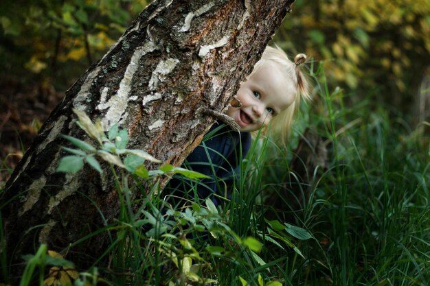 Photo portrait d'une fille sur un tronc d'arbre dans la forêt