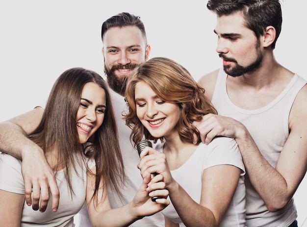 Portrait de filles et de gars heureux chantant dans un microphone sur fond blanc