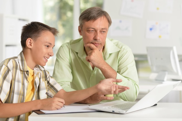 Portrait de fils et père utilisant un ordinateur portable à la maison