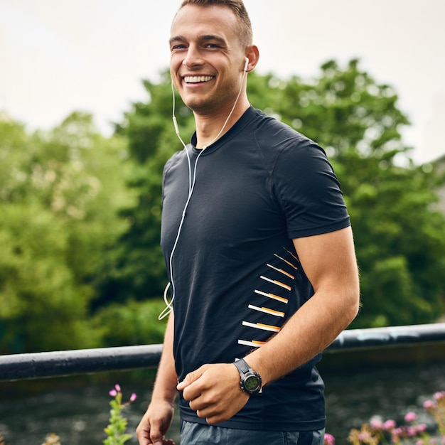 Portrait de fitness et homme avec des écouteurs pour l'écoute de l'ouïe et podcast avec motivation pour l'exercice coureur masculin en plein air et entraînement avec de la musique pour le bien-être course et cardio pour l'entraînement