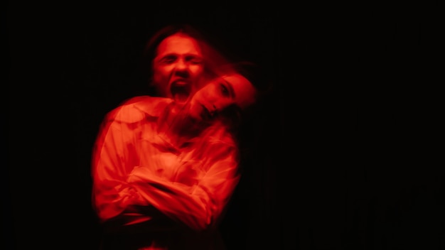 Portrait flou abstrait d'une femme psychotique souffrant de troubles mentaux avec des lumières rouges sur fond noir