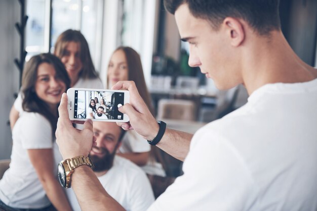 Portrait de flou des meilleurs jeunes amis heureux avec les mains tenant le téléphone au premier plan