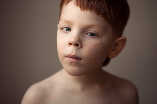 Un portrait fort d'un garçon de 5-6 ans, souriant, aux cheveux roux et aux taches de rousseur