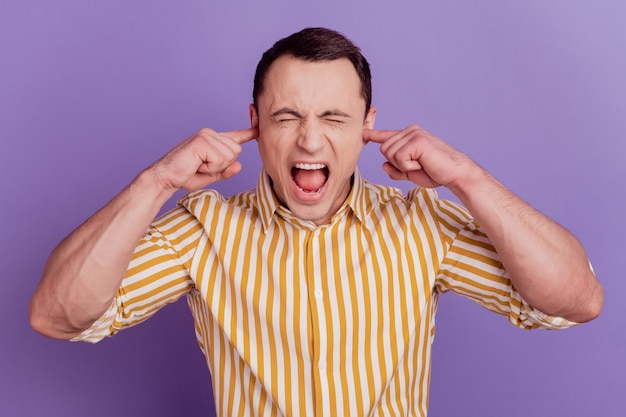 Portrait de fou évitant les doigts de gars couvrent les oreilles crient les yeux fermés sur fond violet