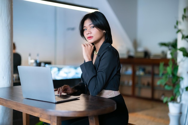 Photo portrait de freelance asiatique femme d'affaires travaillant occasionnellement avec un ordinateur portable dans un café intérieur dans un café arrière-plan d'affaires exprimé confiance enhardir et concept réussi