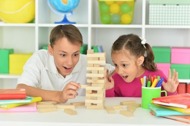 Portrait de frère et sœur jouant avec des blocs de bois à la salle de jeux