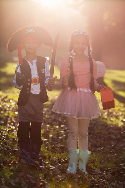 Photo portrait de frères et sœurs souriants portant des costumes au parc