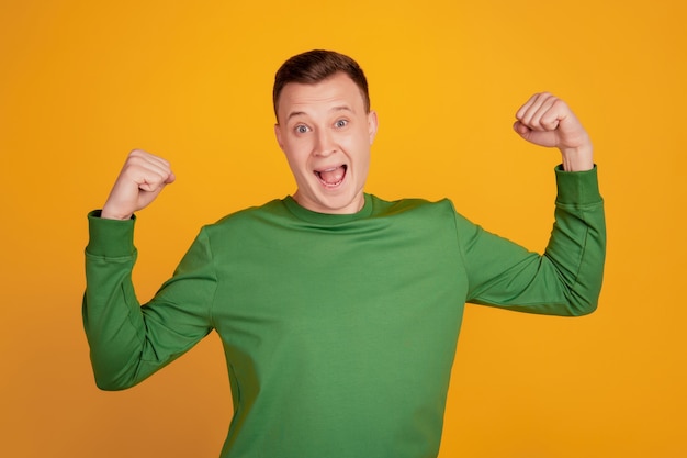 Portrait de gagnant fou positif guy lever les poings crier célébrer la victoire sur fond jaune