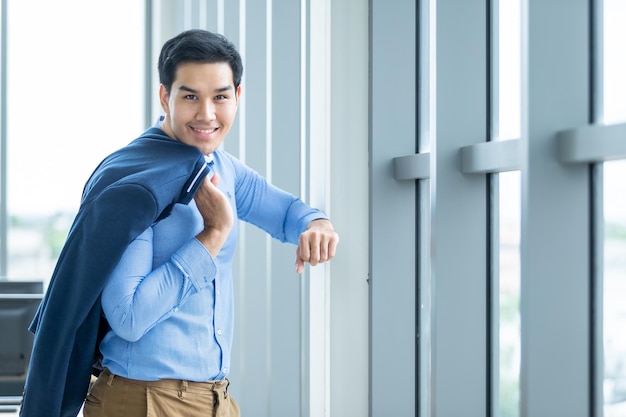 Portrait d'un gagnant de sentiment de succès joyeux beau jeune homme d'affaires asiatique porter un costume d'homme en veste bleue et chemise bleue à la fenêtre Dans le fond de la salle de bureau