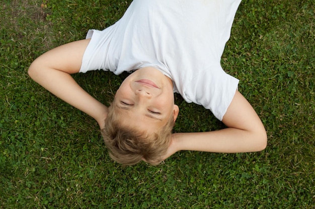 Photo portrait d'un garçon allongé sur un champ herbeux