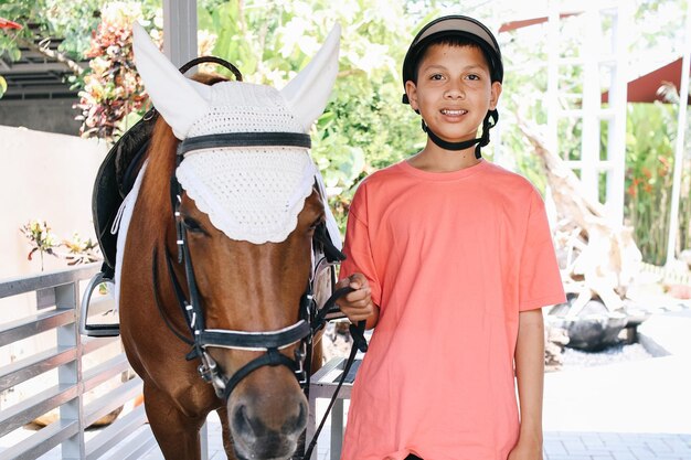 Portrait d'un garçon asiatique et d'un cheval brun