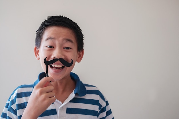 Portrait de garçon asiatique mixte drôle s'amuser avec une fausse moustache