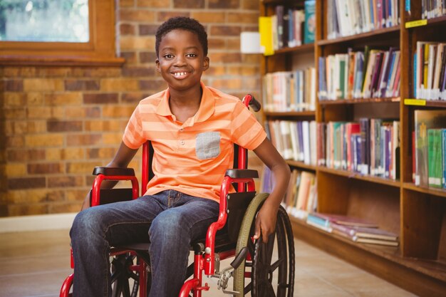 Portrait de garçon assis en fauteuil roulant à la bibliothèque