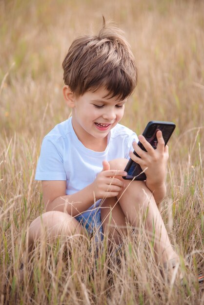 portrait garçon assis sur l'herbe avec téléphone