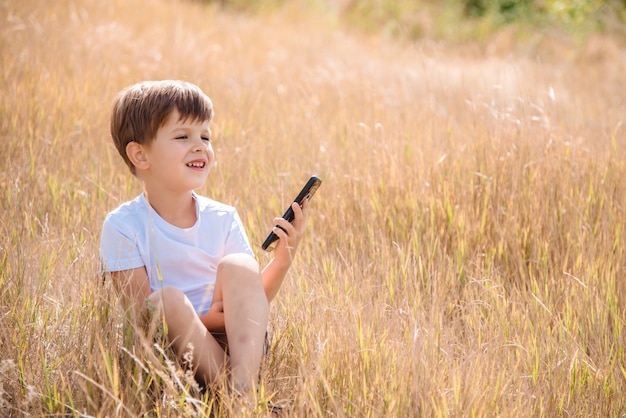 portrait garçon assis sur l'herbe avec téléphone