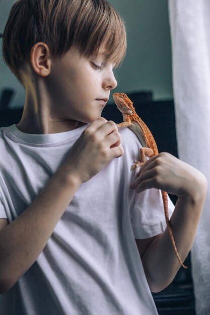 Portrait d'un garçon avec une barbe rouge agama iguana petit enfant jouant avec un reptile focus sélectif