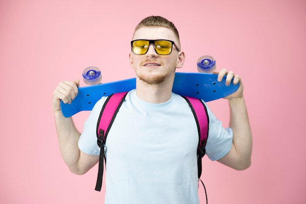 Portrait de garçon barbu américain tenant pennyboard sur l'épaule et souriant