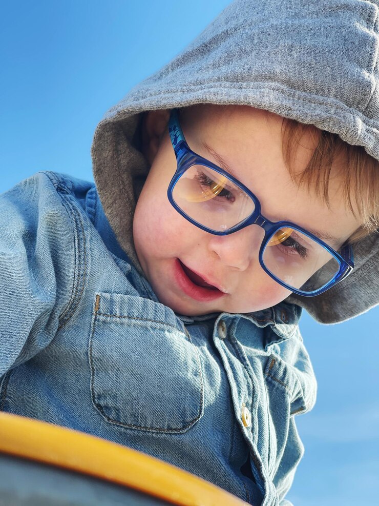 Photo portrait d'un garçon en bas âge avec des lunettes contre le ciel bleu