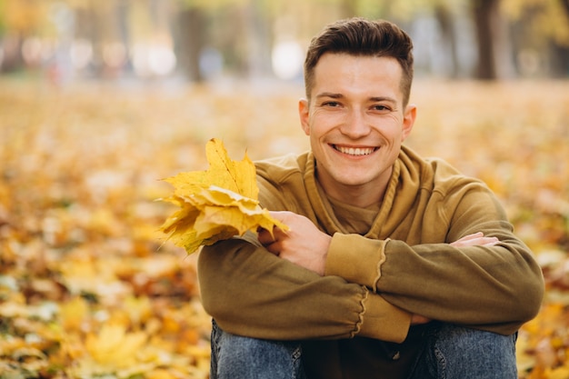 Portrait de garçon beau et heureux avec un bouquet de feuilles jaunes souriant