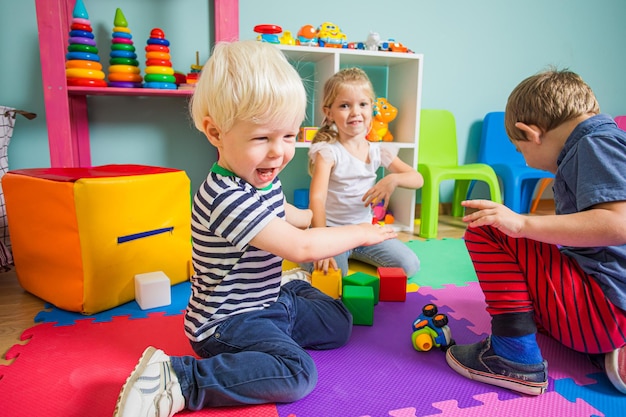 Portrait D'un Garçon Bouleversé Et Ctying à L'école Maternelle Un Joli Garçon Blond Est Intimidé Par Des Enfants à La Maternelle Salle De Jeux Avec De Nombreux Jouets Colorés Et Des Enfants Jouant Sur Un Sol