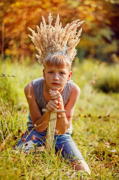 Portrait Garçon avec une couronne sur la tête et une épée dans les mains.