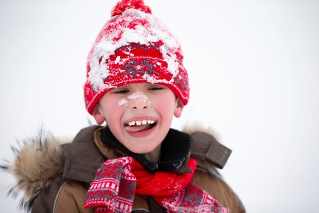 Portrait d'un garçon dans un chapeau d'hiver dans la neige. Un enfant joyeux joue un jour d'hiver.