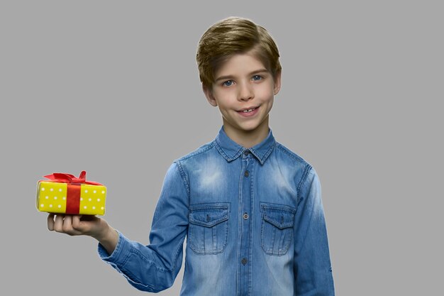 Portrait de garçon enfant mignon posant avec boîte-cadeau. Beau petit garçon tenant la boîte présente et regardant la caméra. Concept de joyeuses fêtes.