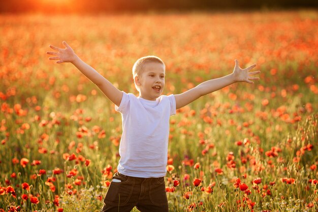 Portrait d'un garçon heureux sur un champ de pavot en été