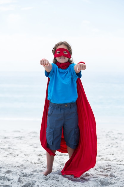 Portrait d'un garçon heureux en costume de super-héros à la plage