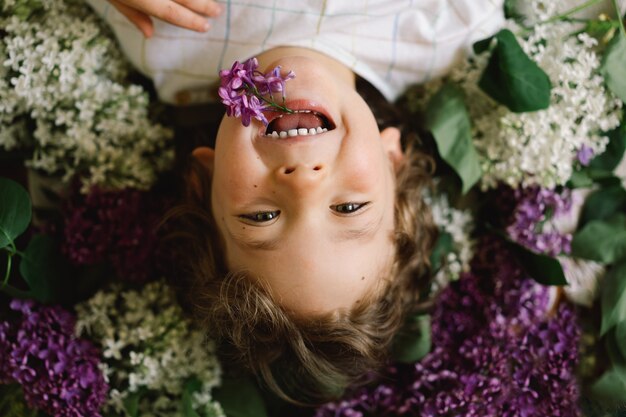 Portrait d'un garçon heureux en fleurs lilas enfance heureuse