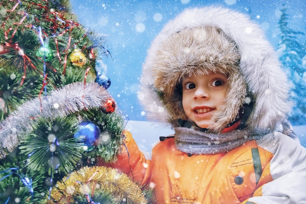 Portrait d'un garçon heureux près du sapin de Noël avec des cadeaux