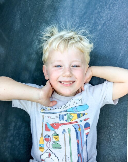 Photo portrait d'un garçon heureux et souriant qui s'amuse sur une toboggan dans le parc