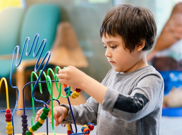 Portrait garçon intérieur d&#39;âge préscolaire jouant dans le club pour enfants avec ton vintage, enfant s&#39;amusant à jouer des jouets colorés dans la salle de jeux pour enfants. Kid garçon jouant avec des jouets éducatifs à la maternelle. Concept d&#39;éducation