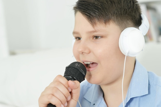 Portrait de garçon avec microphone chantant à la maison