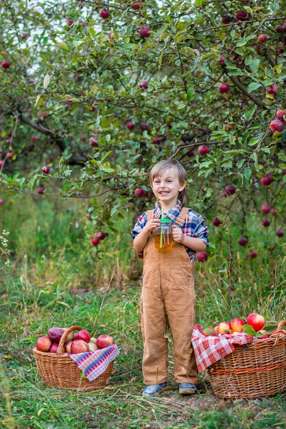 Portrait d'un garçon mignon dans le jardin avec une pomme rouge Récolte d'automne de pommes