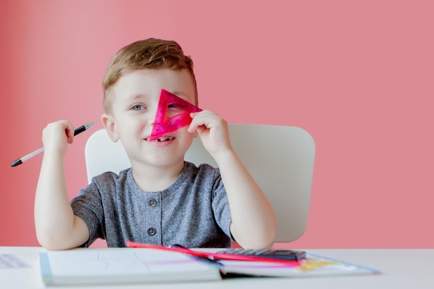 Portrait d'un garçon mignon à la maison faisant ses devoirs Petit enfant concentré écrivant avec un crayon coloré à l'intérieur École primaire et éducation Enfant apprenant à écrire des lettres et des chiffres