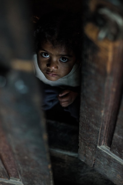 Photo portrait d'un garçon mignon regardant à travers une porte ouverte