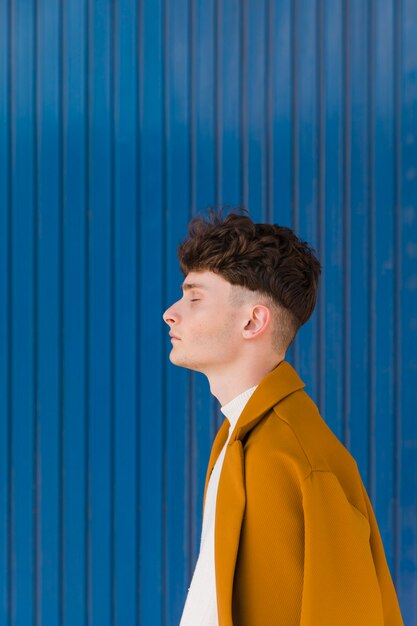 Portrait d'un garçon à la mode contre le mur bleu