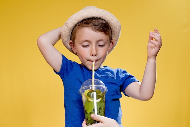 Portrait de garçon portant un chapeau et quelqu'un tient une limonade fraîche