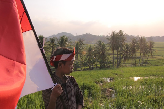 portrait d'un garçon portant un drapeau rouge et blanc avec vue sur les rizières