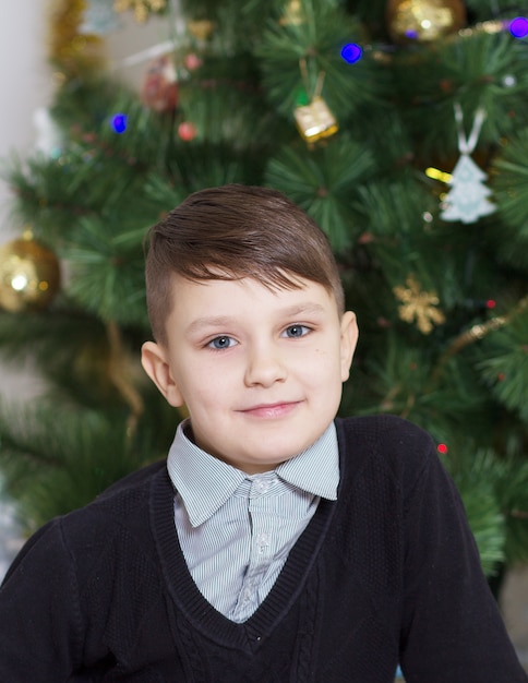portrait d'un garçon près de l'arbre du nouvel an