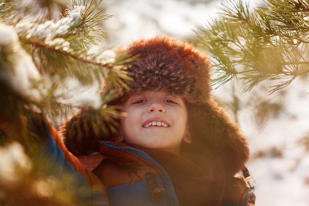 Portrait de garçon souriant dans une forêt enneigée en hiver