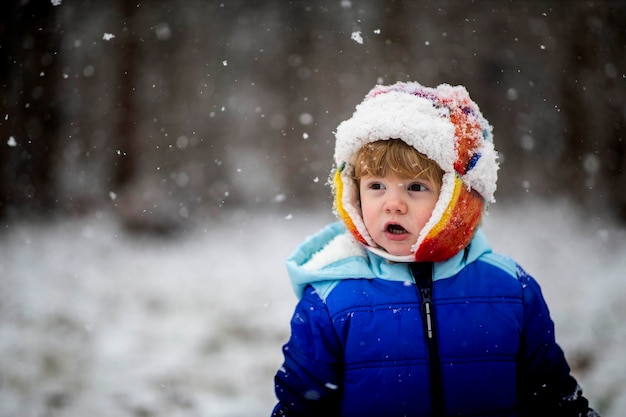 Photo portrait d'un garçon souriant debout dans la neige