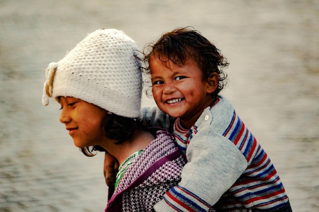 Photo portrait d'un garçon souriant porté par sa sœur contre la mer