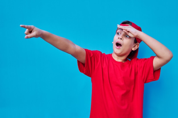 Un portrait de garçon surpris en bonnet rouge et pointes de t-shirt avec le doigt. Copier l'espace ...