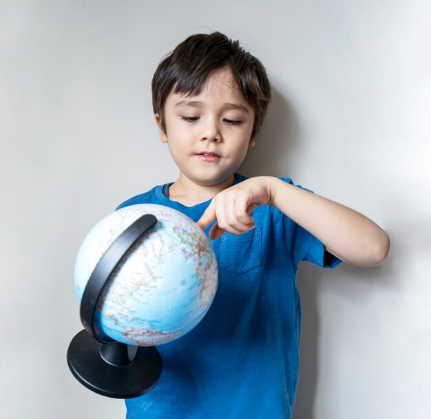 Portrait d'un garçon tenant un globe terrestre
