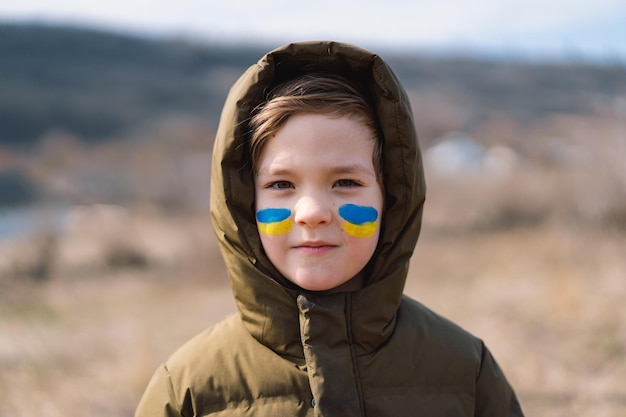 Portrait d'un garçon ukrainien avec un visage peint aux couleurs du drapeau ukrainien