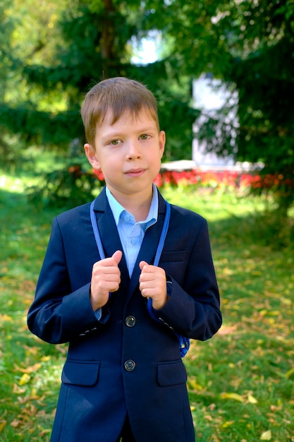 Photo portrait d'un garçon en uniforme scolaire écolier dans la rue garçon sérieux look enfant avec sac à dos le premier jour d'école