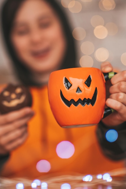 Portrait d'un garçon zoomer authentique candide posant avec une tasse de thé et des bonbons à la maison fête d'Halloween