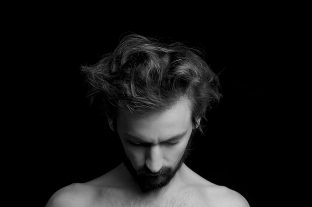 Portrait d'un gars avec une barbe et des cheveux ébouriffés sur fond noir